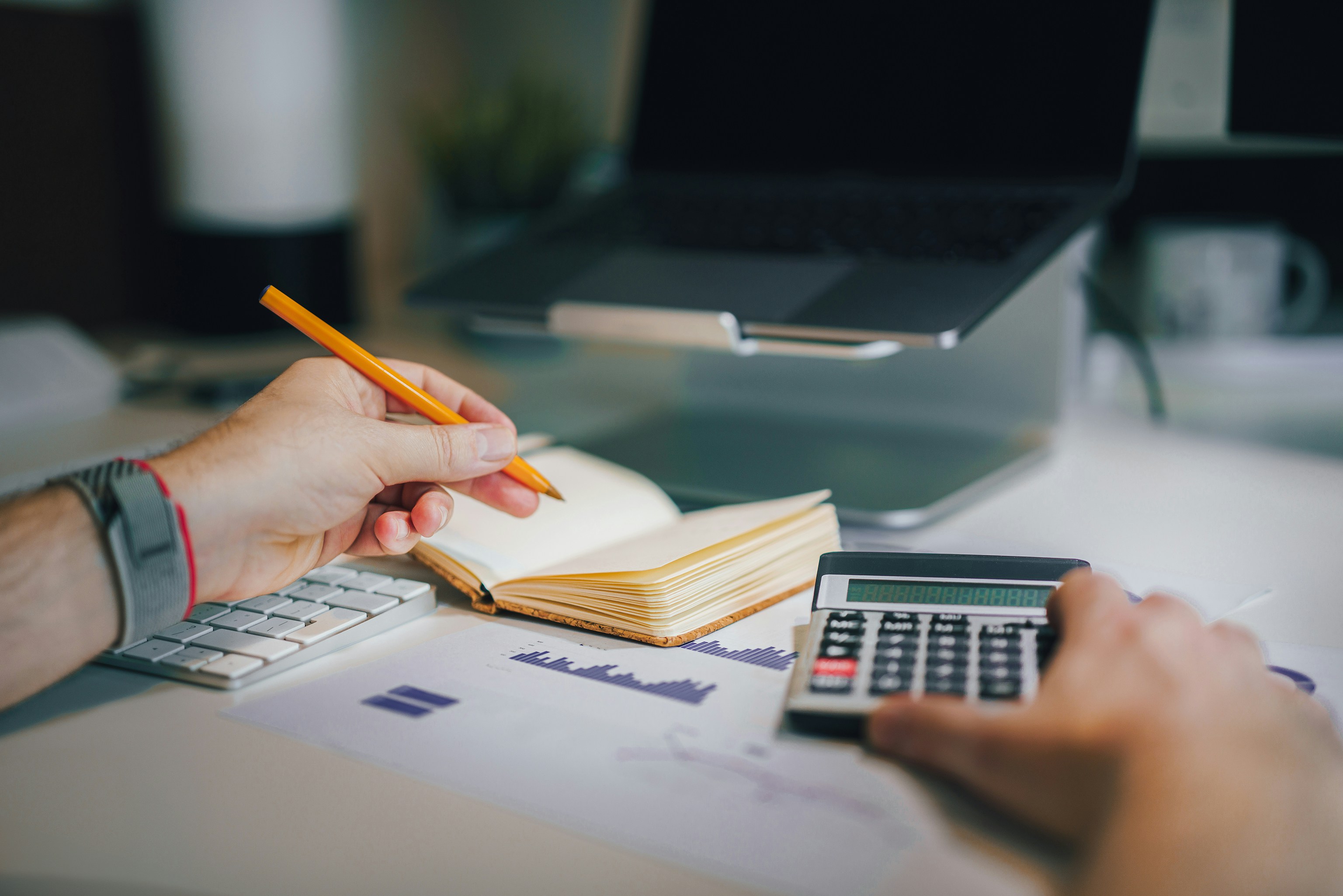 Hands using a calculator and notebook to analyze fleet maintenance cost data, illustrating hidden budget leaks