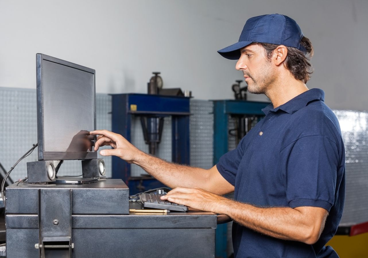 Shop technician reviewing vehicle data on a computer in a service workshop
