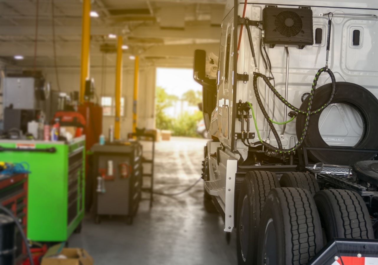Semi truck parked in a fleet service bay with tools and equipment ready for repair work