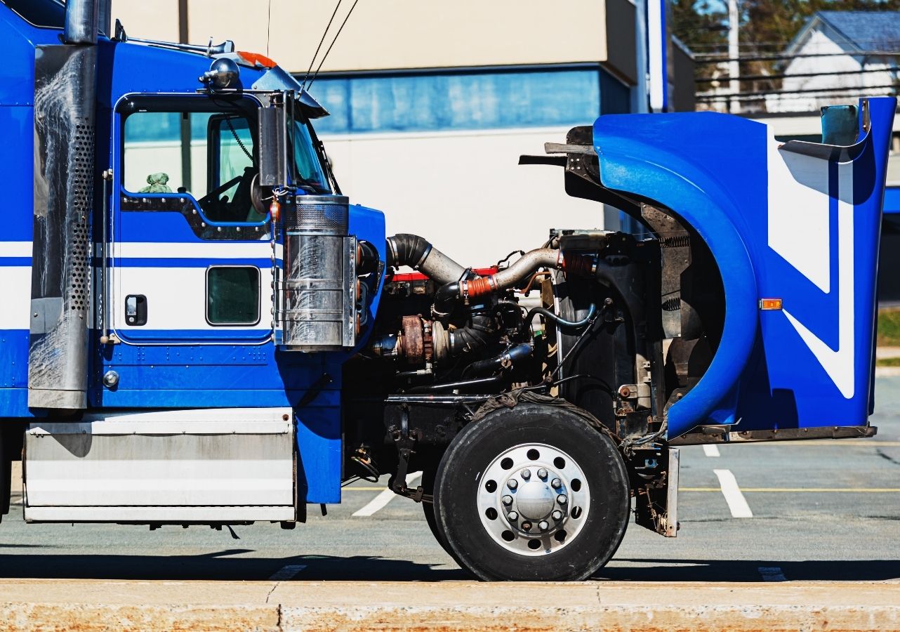 Blue semi truck with the hood tilted forward exposing the engine and turbo for service