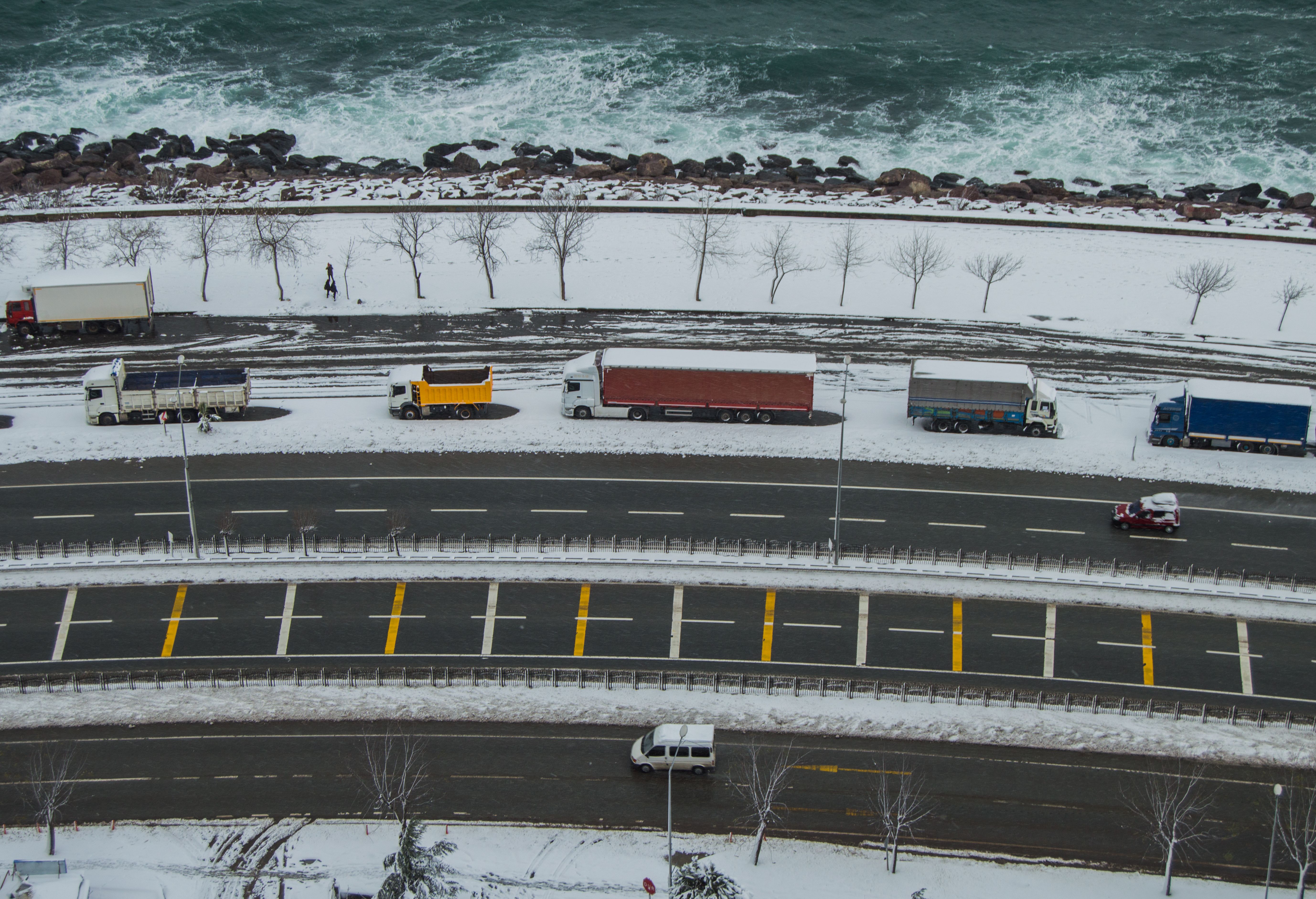 Aerial view of several trucks parked along a snow-covered coastal highway